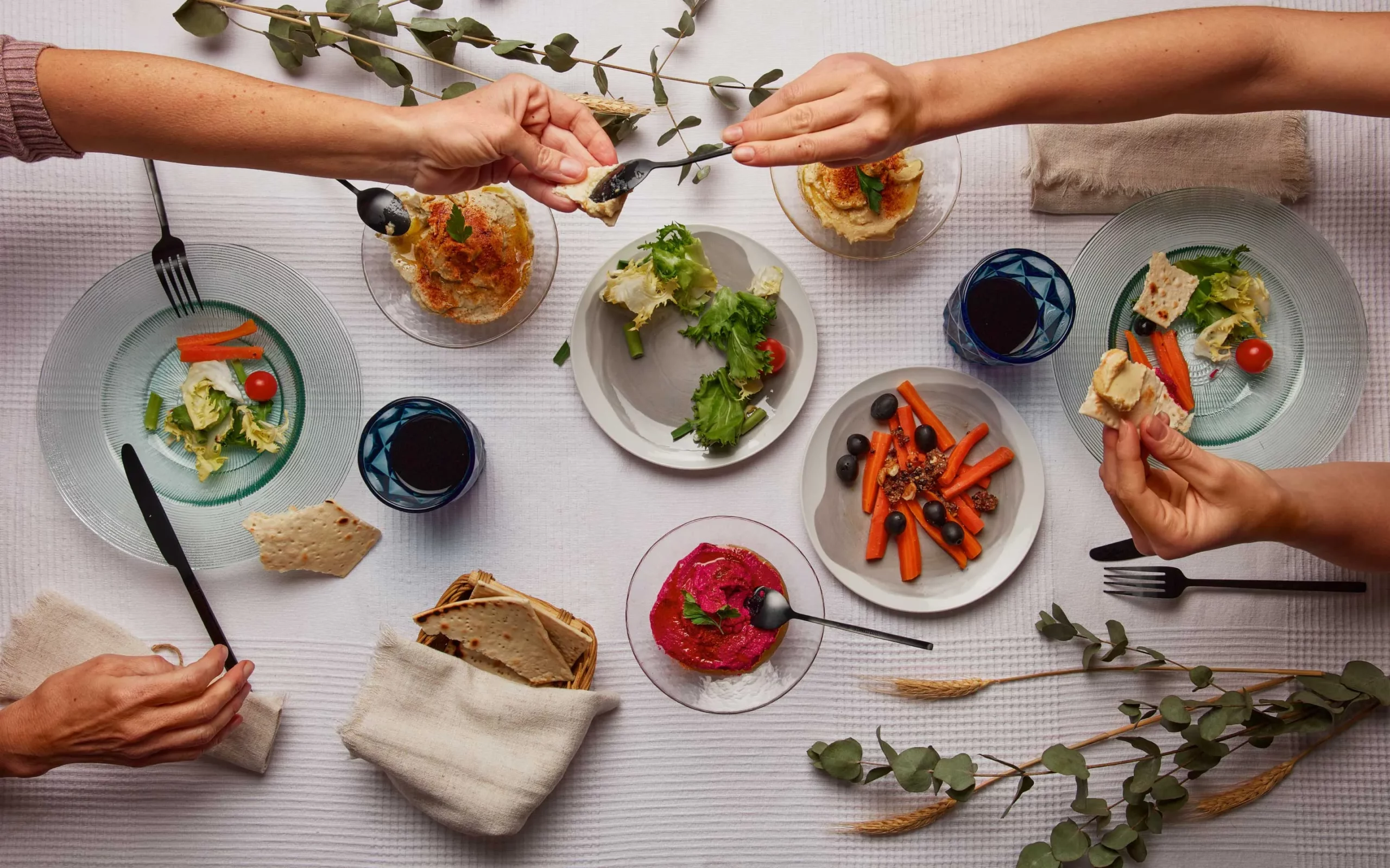 Manos compartiendo platos saludables en una mesa elegante, celebrando la diversidad culinaria. experiencias gastronómicas saludables, restaurantes sostenibles, compartir comida con propósito.